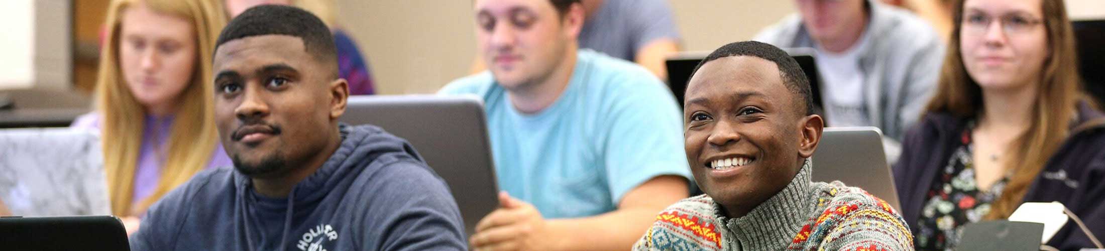 Two male students watching instructor in class