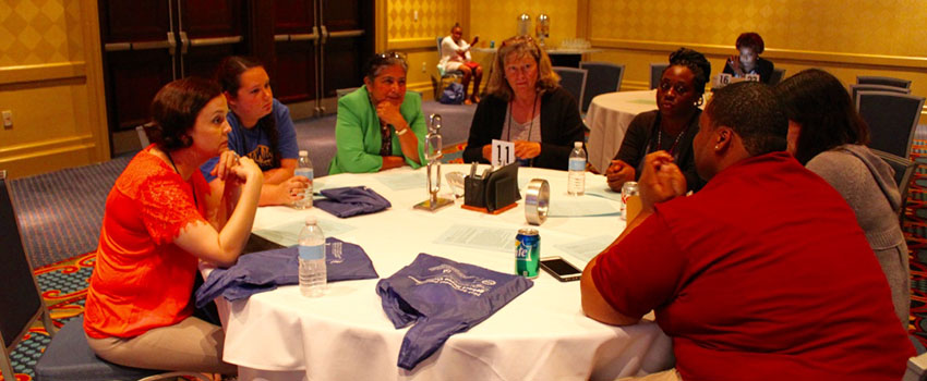 A group of men and women talking around a round table.