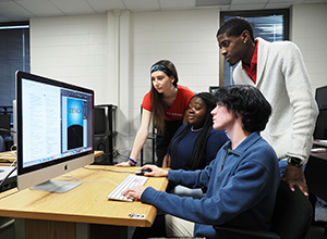 Communication students looking at computer monitor together at internships.