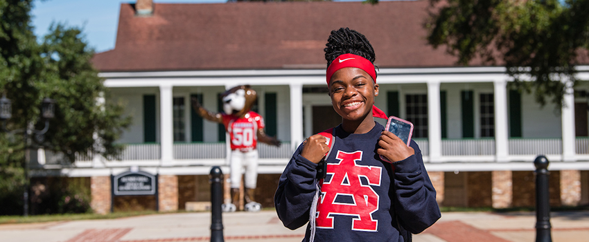 USA Student smiling in front of Southpaw statue.