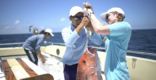 Two people holding up a fish on a boat.