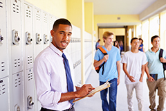 Teacher standing in hall in front of lockers.