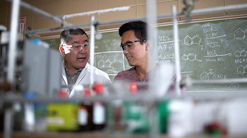 Male student working in lab with Dr. Yet.