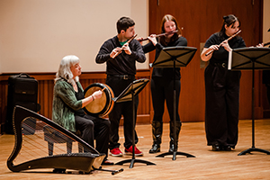 Three students with teacher playing music.