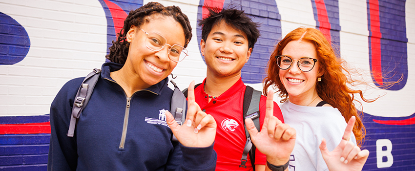 Three South Alabama students holding up the J sign for Jaguars.