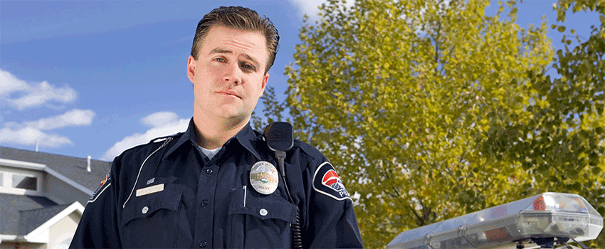 Police officer standing outside in front of a police car.