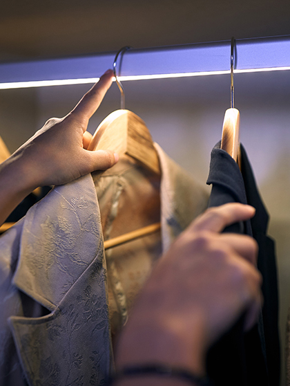 Hands going through clothes closet.