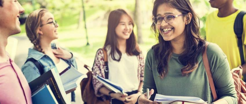 Students laughing holding books outside