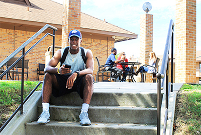 Male student sitting on steps looking at phone