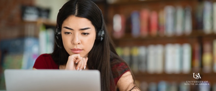 Young woman wearing headphones looking at her laptop.