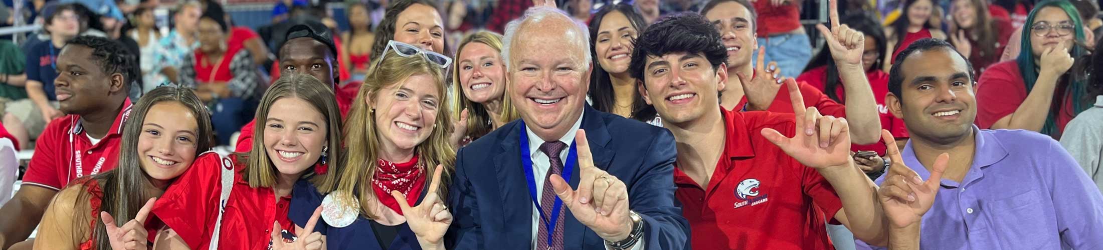 President Bonner holding up J sign with a group of students.