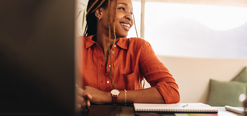 Woman in office working and smiling at desk.