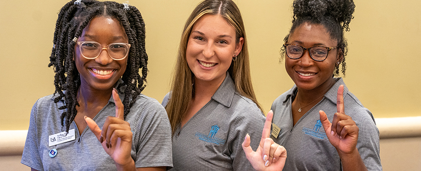 Three female students holding up J sign.