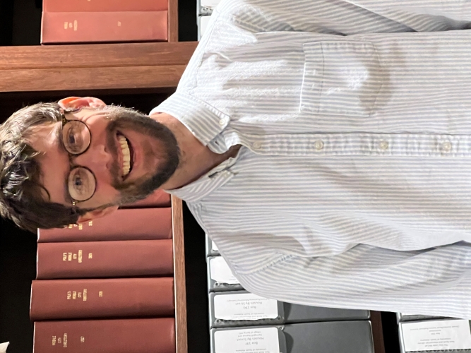 Charles Herring stands in front of the bookshelves in the reading room.