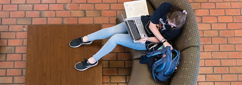 Student studying with laptop in lap.