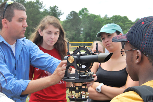 Professor working with wether equipment outside with students.